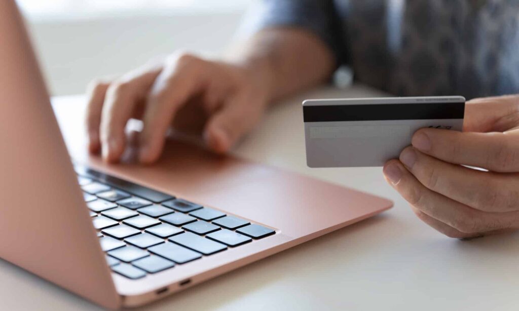 Close up of hands shopping/paying online with laptop and credit card